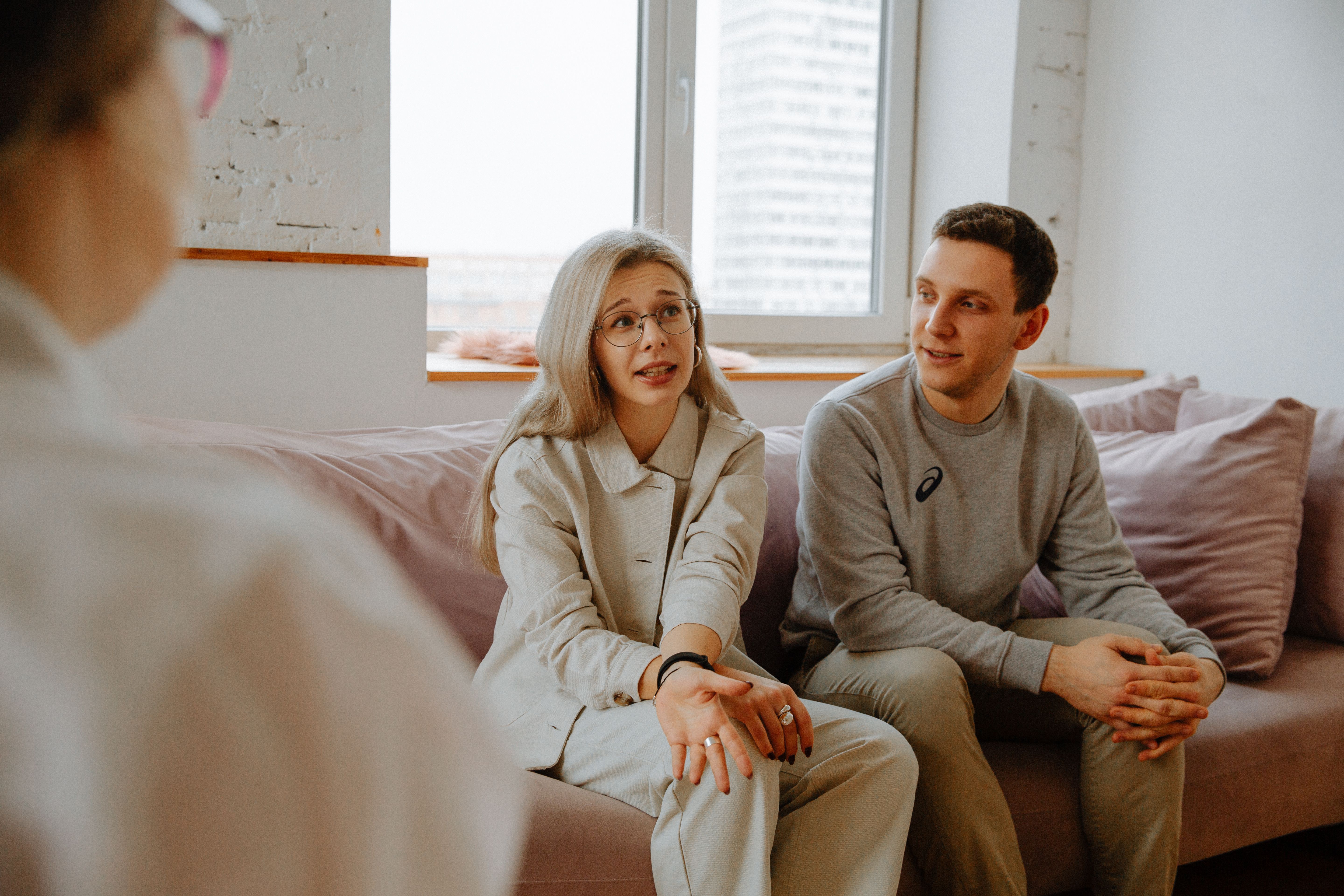 A couple and therapist engaged in a discussion during a therapy session indoors about cheating.