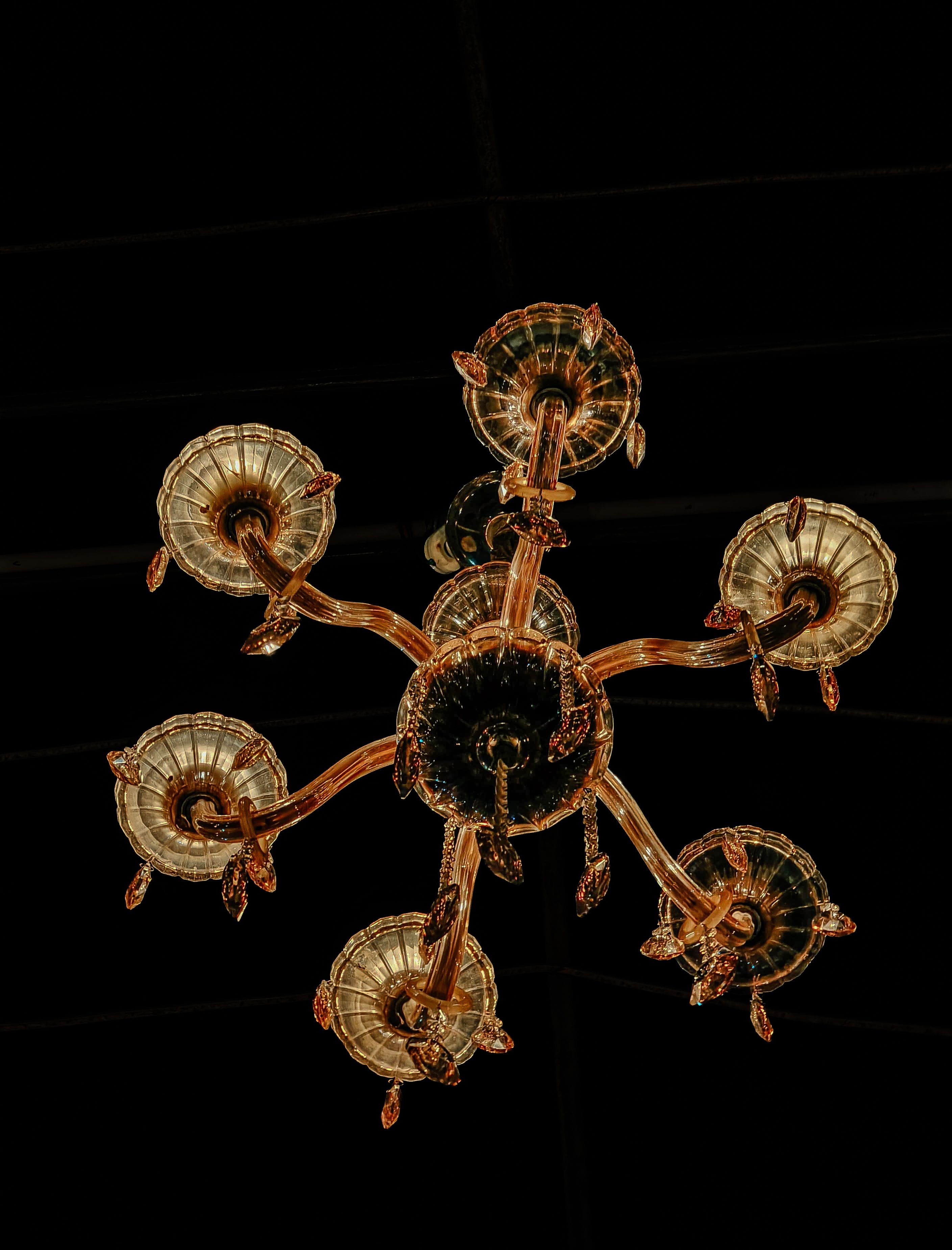 An ornate vintage chandelier with glass details against a dark background, exuding luxury and sophistication.