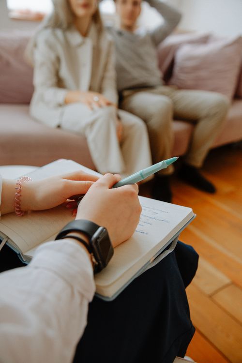 Free A therapist takes notes while counseling a couple in an indoor session. Stock Photo