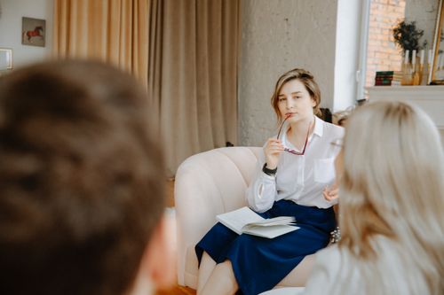 Free Counselor in a therapy session, attentively listening to clients indoors. Stock Photo