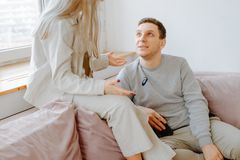 A couple having a conversation on a pink couch in a well-lit modern apartment.