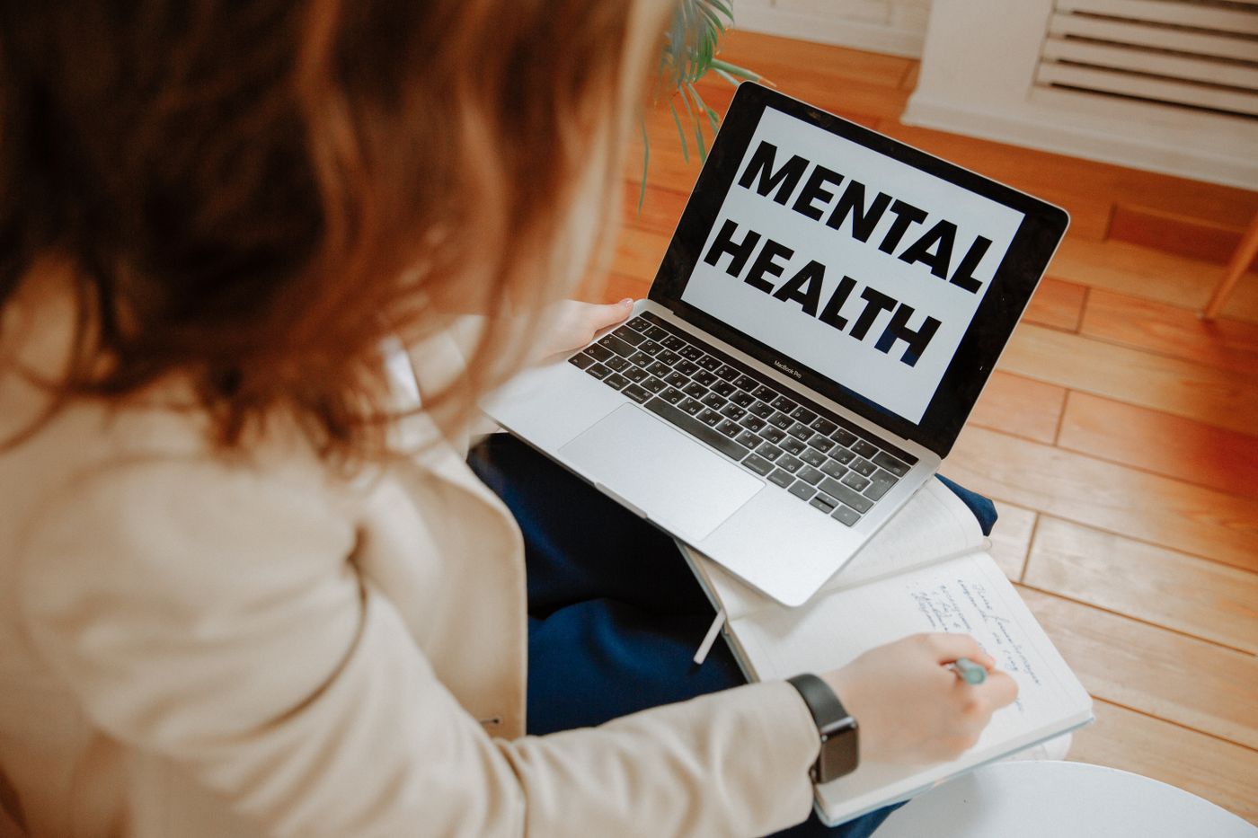 Person taking notes during an online mental-health session using a laptop