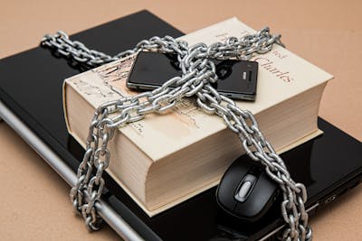 a phone on a book on a laptop all bound with chains and locks