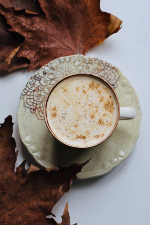 Free Top view of latte coffee in a vintage cup surrounded by autumn leaves, evoking warmth. Stock Photo