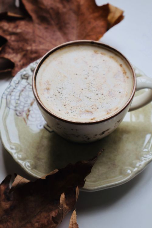 Free A warm cup of cappuccino surrounded by autumn leaves, perfect for fall relaxation. Stock Photo