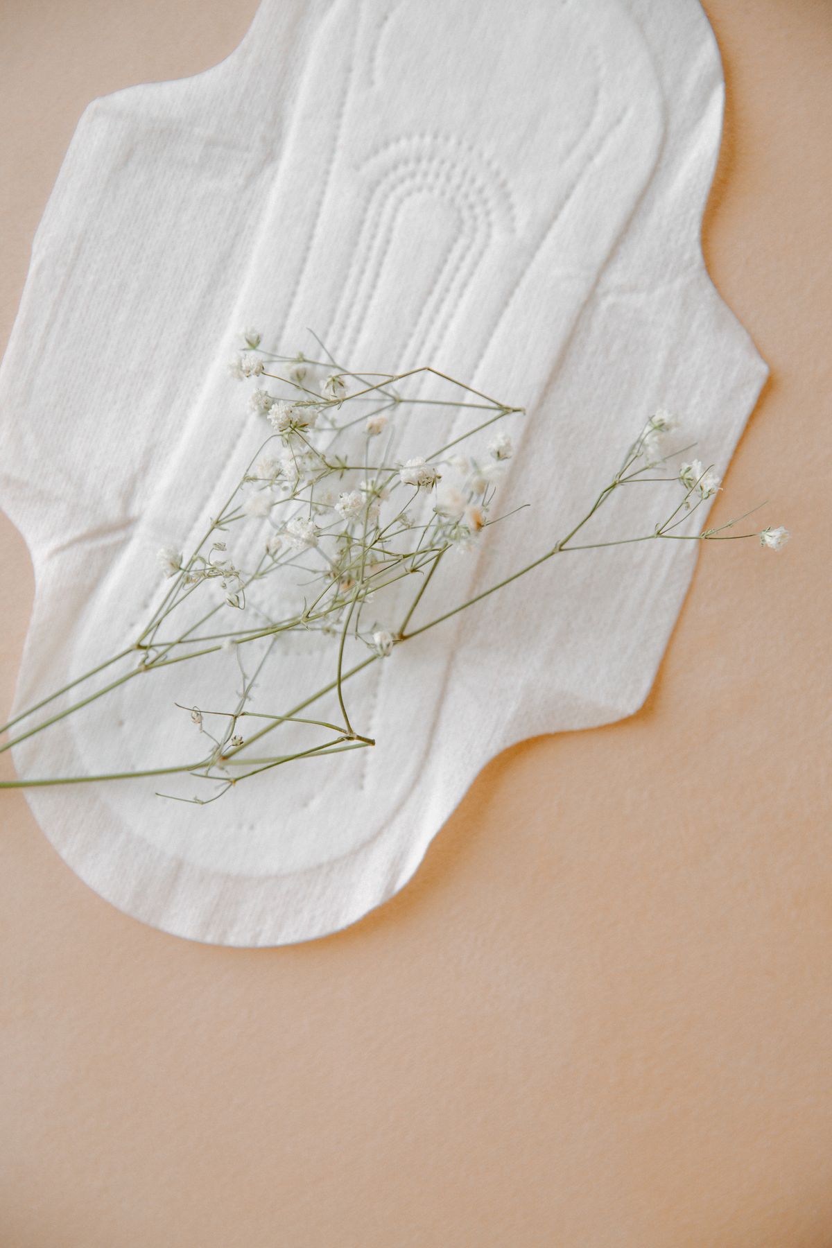 Sanitary pad with delicate flowers on a neutral surface representing feminine care