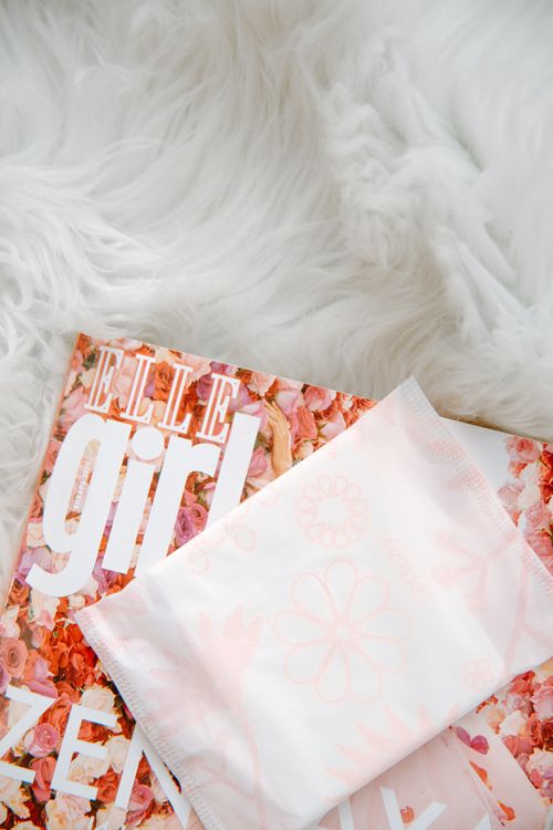 Free Sanitary pad placed on a fashion magazine with a floral theme, conveying elegance and hygiene. Stock Photo