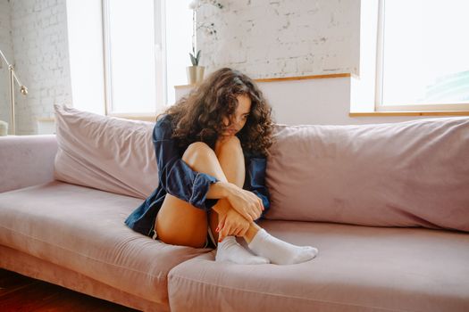 一名年轻女子坐在舒适的沙发上，显得若有所思