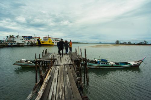 Free A rustic dock with people overlooking boats on the water in Bangka Belitung Islands, Indonesia. Stock Photo