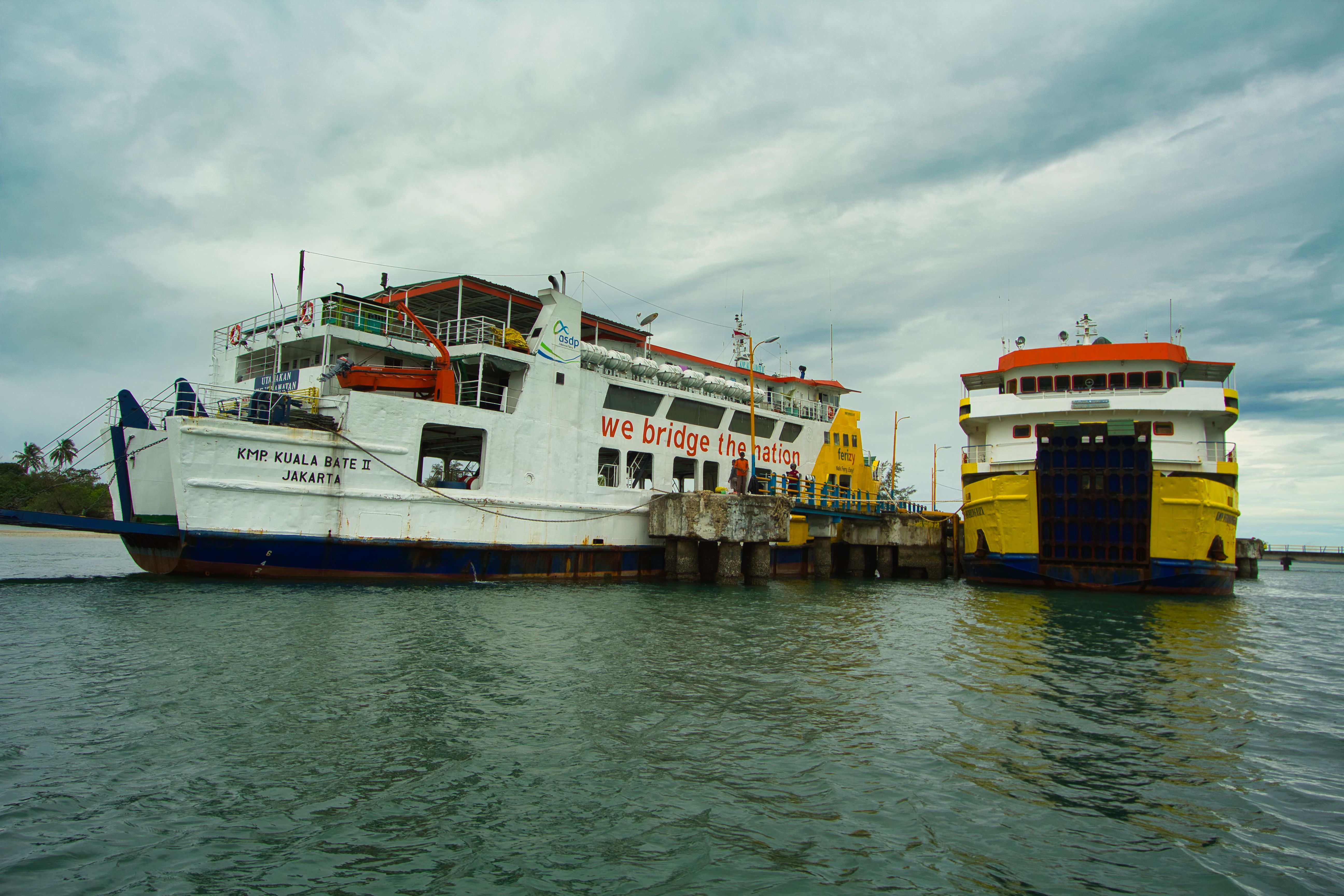 Two ferries docked at Bangka Belitung Islands harbor in Indonesia under cloudy skies.