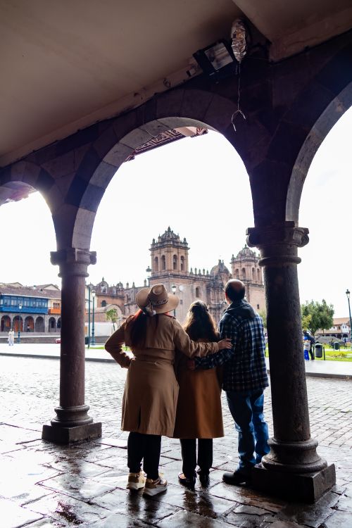 Free Three tourists view Cusco's historic architecture through an archway, capturing a blend of culture and travel. Stock Photo