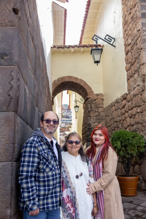 Free A family of three posing in a historic stone alleyway with traditional architecture. Stock Photo