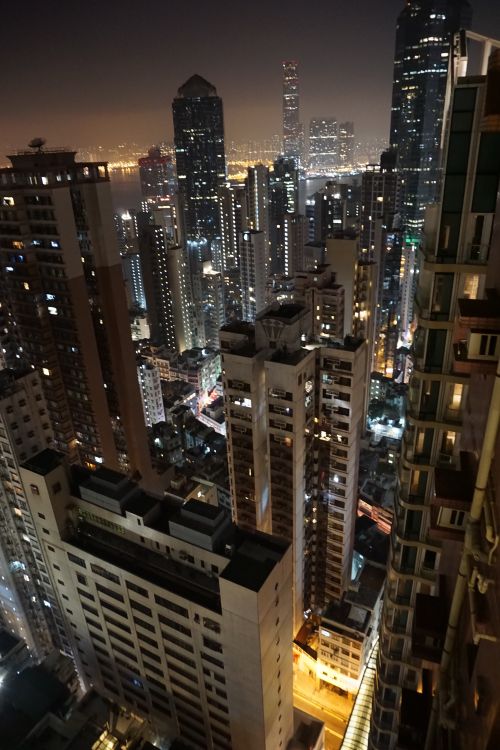 Free A breathtaking aerial view of Hong Kong's vibrant skyline at night, showcasing towering skyscrapers illuminated against the city lights. Stock Photo