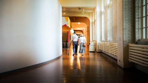 Free A senior couple strolling in a bright, modern hallway indoors. Their journey is peaceful and reflective. Stock Photo