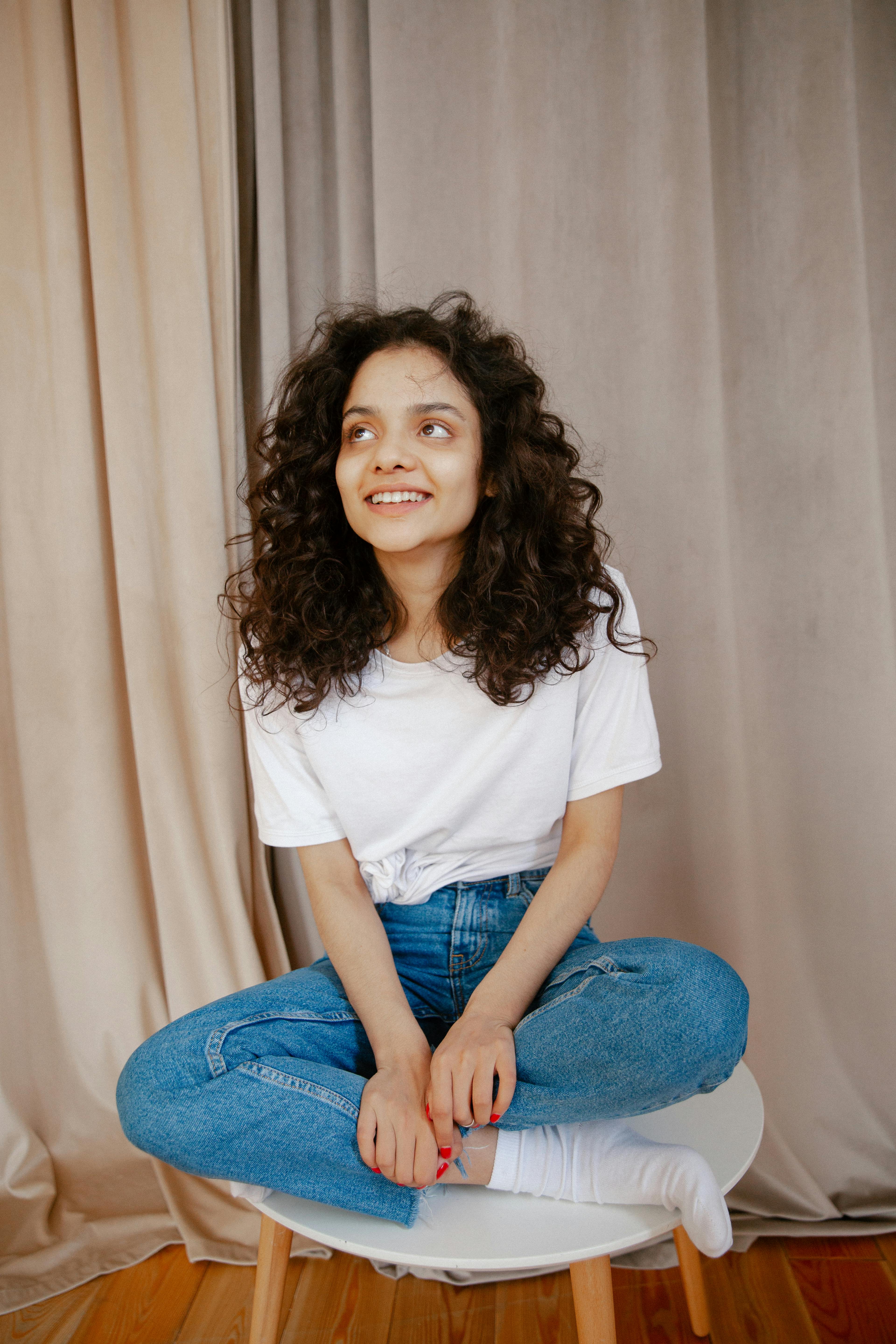 一位面带微笑的年轻女子坐在室内的椅子上，散发着欢乐和放松的气息