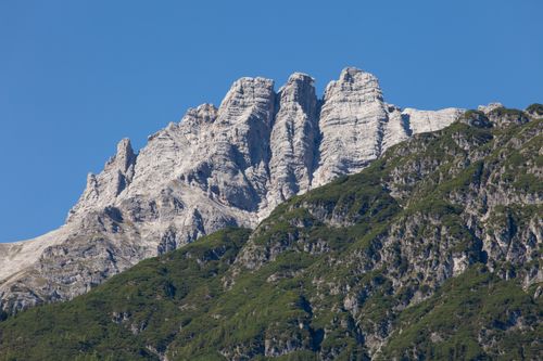 Free Stunning view of rugged alpine peaks with green foliage under a clear blue sky. Stock Photo