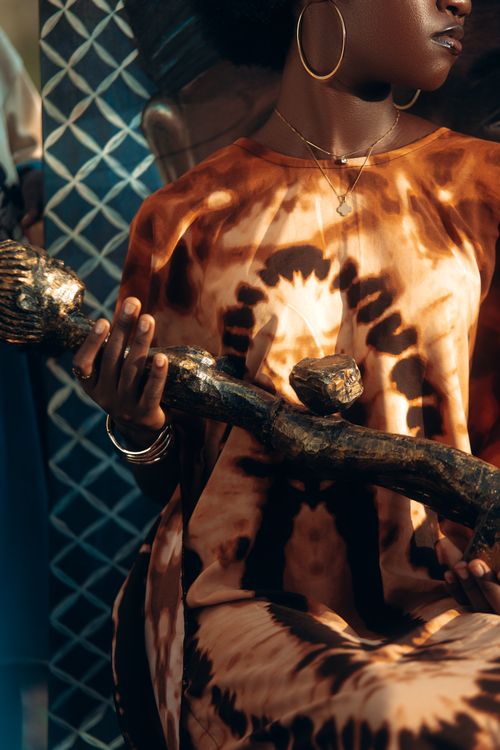 Free Artistic shot featuring a person in tie-dye attire holding a decorative wooden object. Stock Photo