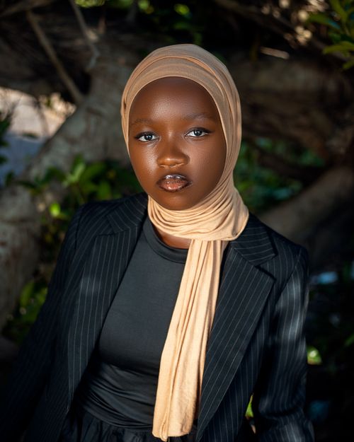 Free Stylish portrait of a woman wearing a hijab and formal attire amidst a natural backdrop. Stock Photo