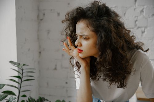 Free A thoughtful young woman with curly hair indoors, displaying a curious expression. Stock Photo