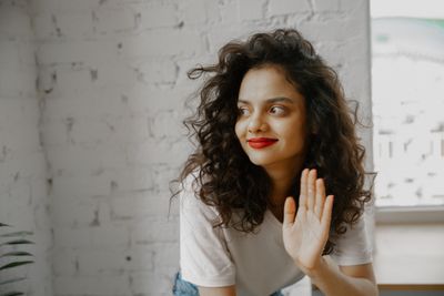 Smiling woman waving hello indoors — Polina Zimmerman on Pexels