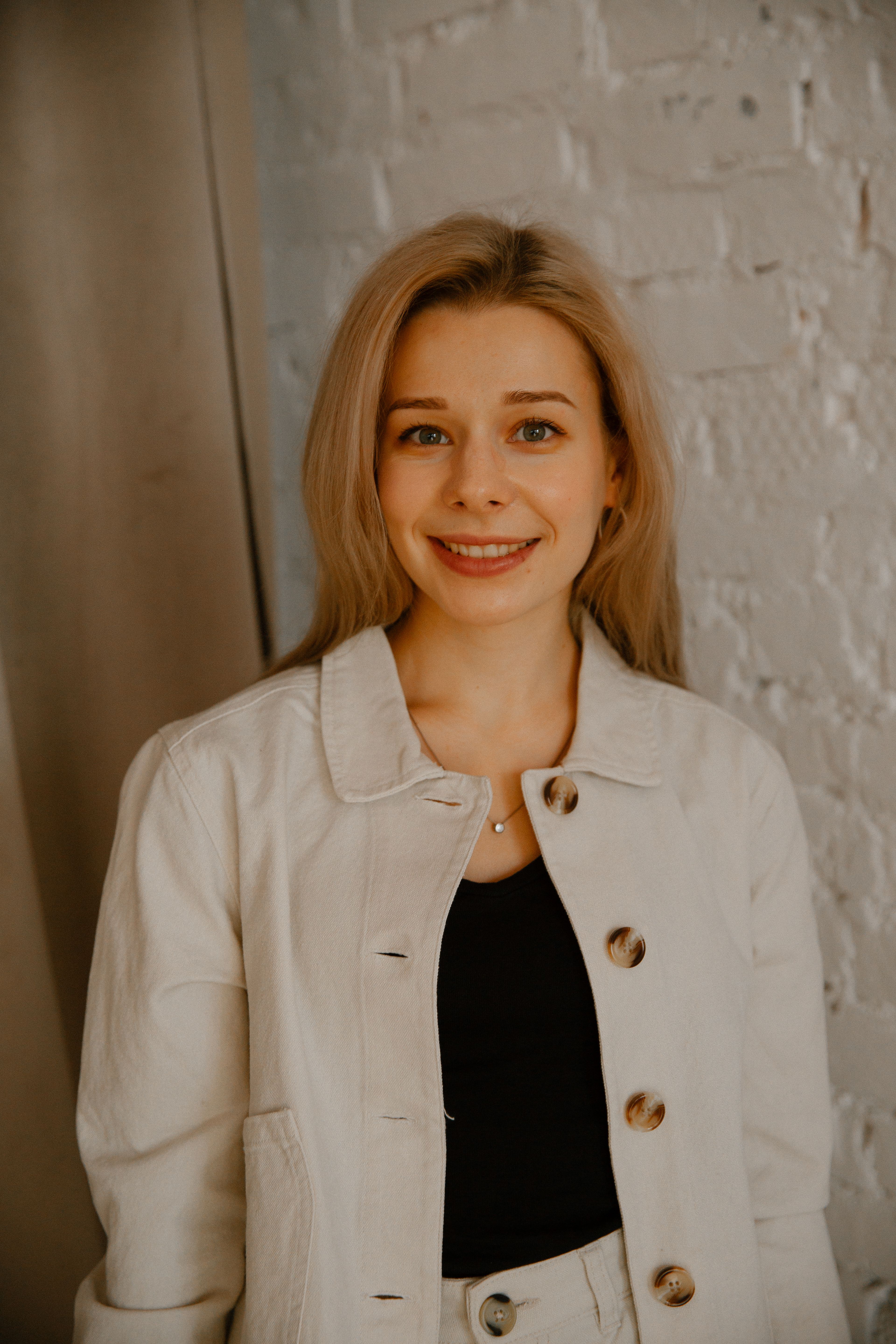 Portrait of a happy woman with blonde hair in casual clothing, standing indoors.
