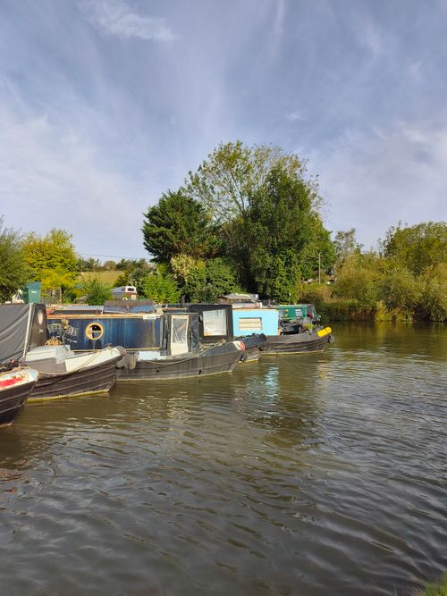 Free Peaceful view of moored boats along a canal surrounded by greenery. Stock Photo