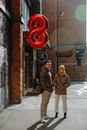 Confident couple with red foil balloon standing on urban street in cold season