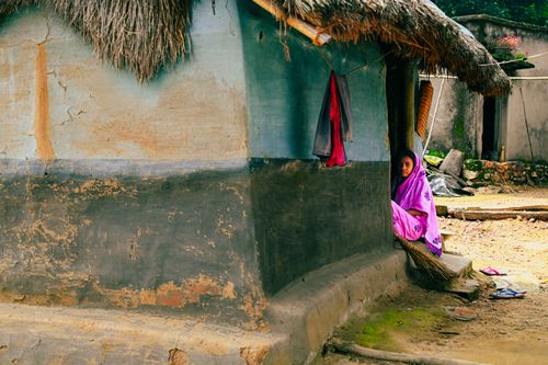 Free A woman in vibrant sari outside a clay hut in Belpahari, India, capturing rural life. Stock Photo