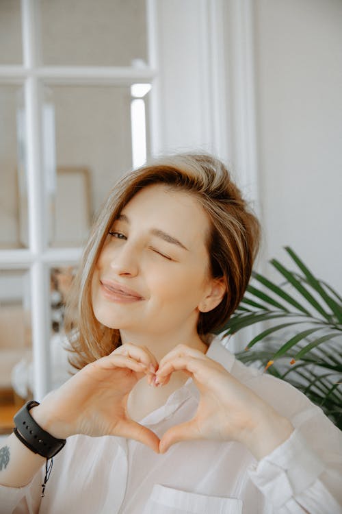 Free Woman in White Dress Shirt Doing Heart Sign Stock Photo