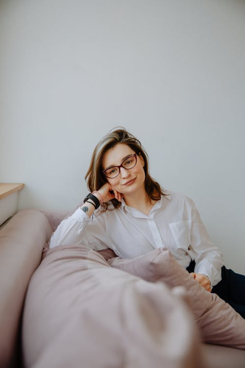 Woman in White Dress Shirt and Black Pants Sitting on Couch