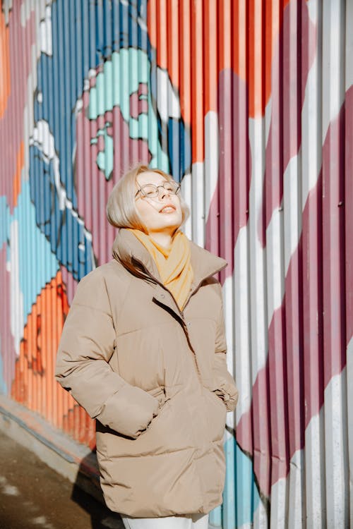 Free Woman in Brown Coat Standing Beside Wall Stock Photo