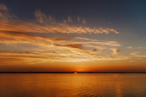 Free Peaceful sunset over a calm lake with dramatic clouds and vibrant colors, perfect for relaxation themes. Stock Photo