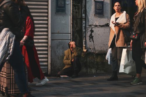 Free A busy İstanbul street with people walking past a man sitting by a wall. Stock Photo