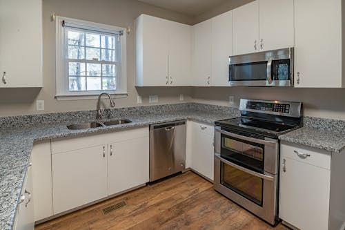 White Wooden Kitchen Cabinet Near White Wooden Framed Glass Window