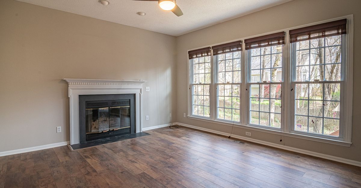 A bright and spacious modern living room interior with a fireplace and large windows.
