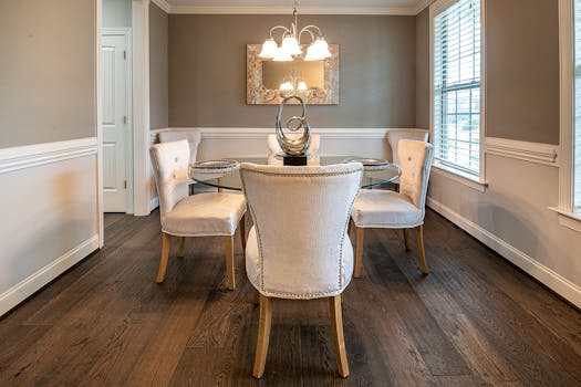 A sophisticated dining room with elegant chairs, a glass table, and tasteful decor.