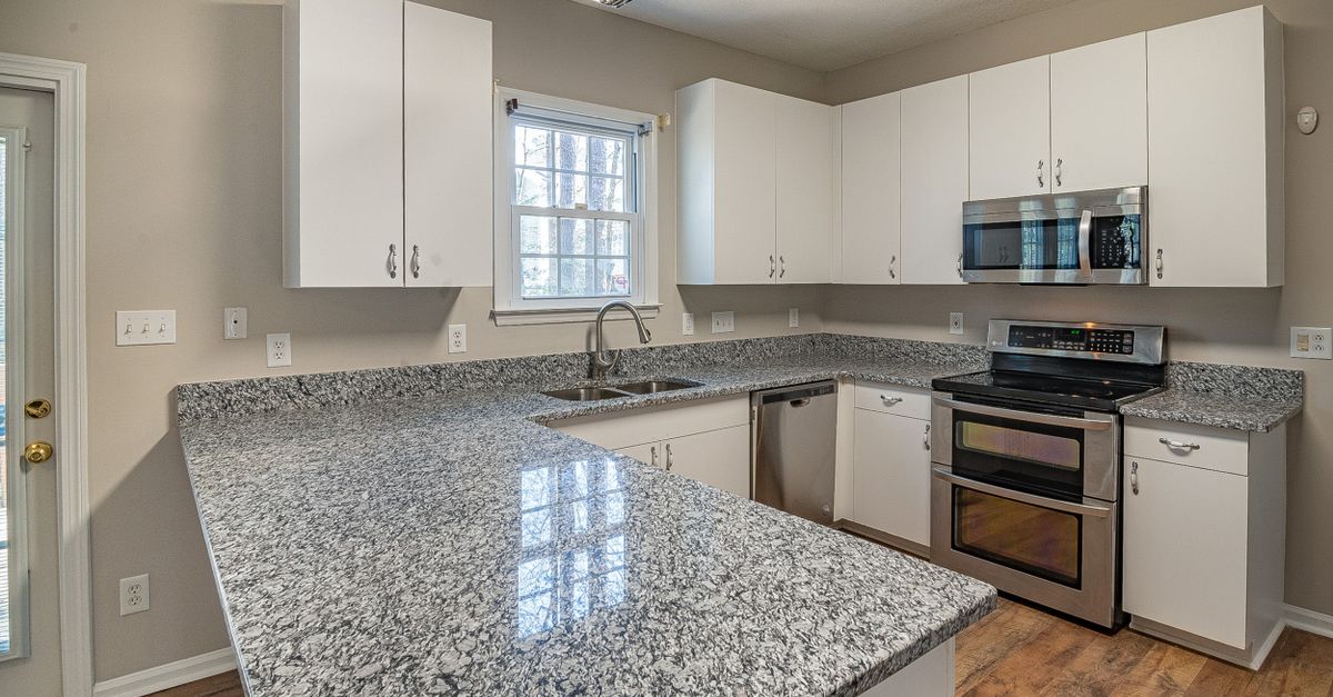 Sleek kitchen design featuring granite countertops, white cabinets, and stainless steel appliances.