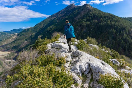 Person in Blue Jacket Standing on Gray Rock Mountain