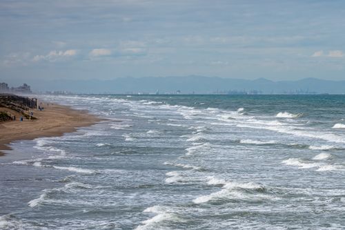 Free Scenic view of Valencia's beachfront with waves breaking on the sandy shore under a cloudy sky. Stock Photo
