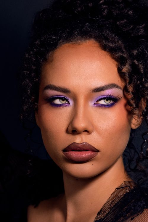 Free Stunning close-up portrait of a woman with purple eyeshadow and curly hair. Stock Photo