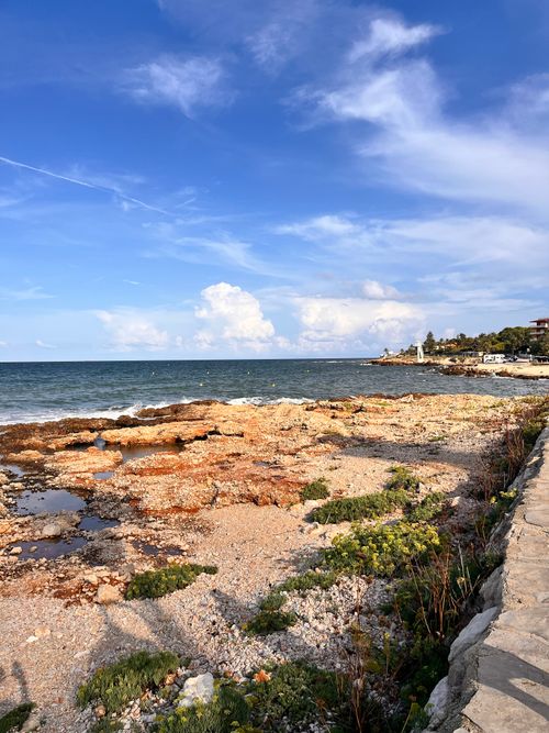 Free A sunny day on the rocky coastline of Dénia, Spain, with clear blue skies and a lighthouse view. Stock Photo