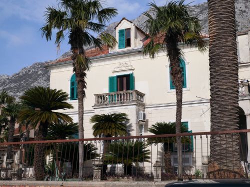 Free Charming historic villa surrounded by palm trees under a bright blue sky. Stock Photo