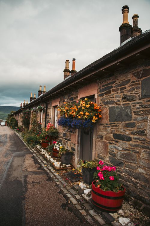 Free Scenic view of stone cottages adorned with vibrant flowers in a picturesque village setting. Stock Photo