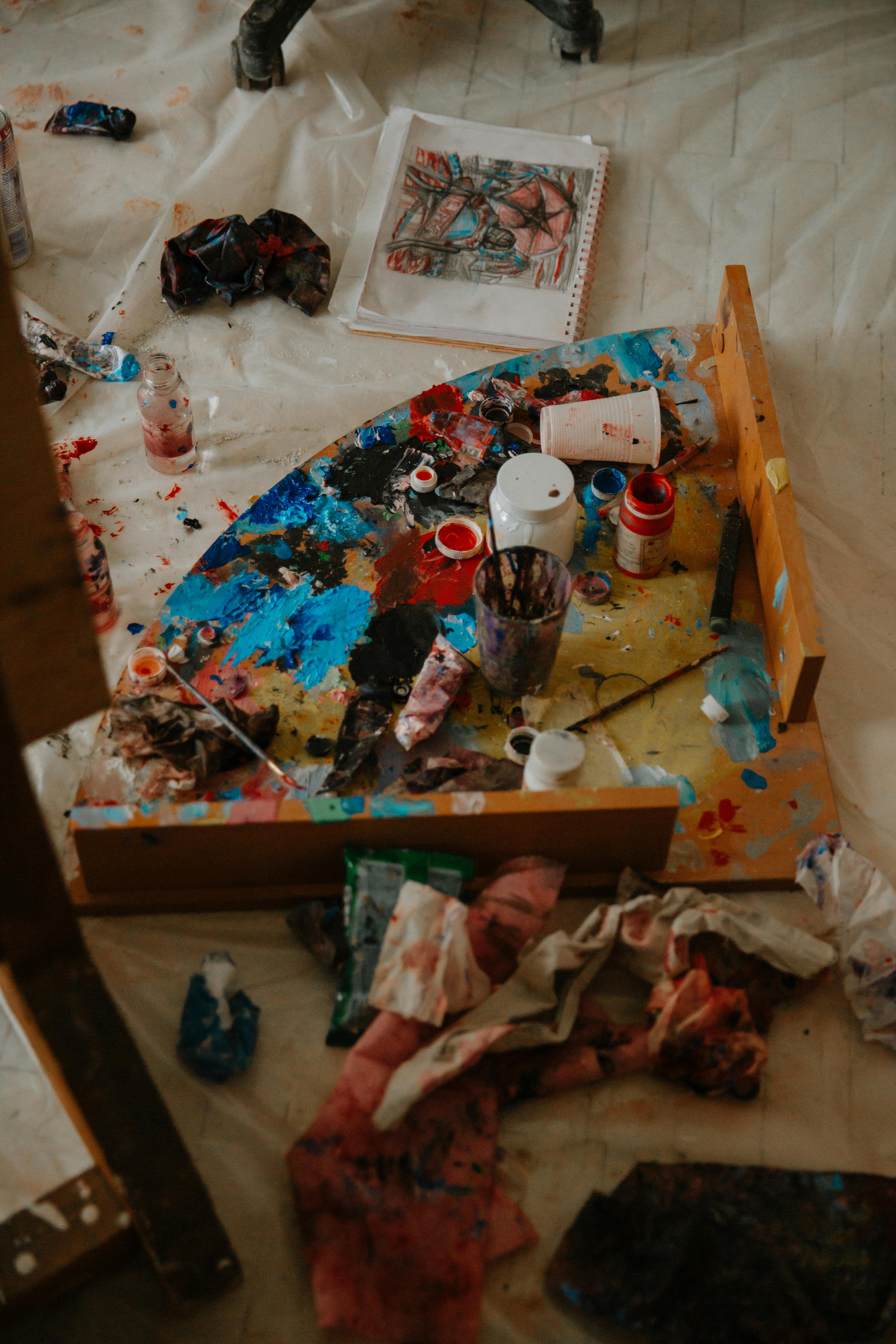 From above of paints on palette near supplies placed on ...