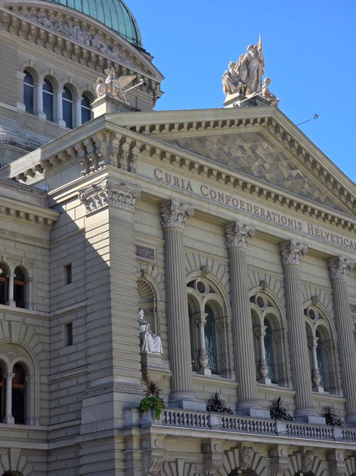 Free Detailed view of the Swiss Federal Palace facade with sculptures and pillars under a blue sky. Stock Photo