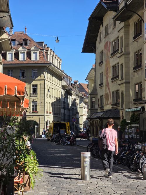 Free Sunny day on a bustling European street with classic architecture and bicycles. Stock Photo