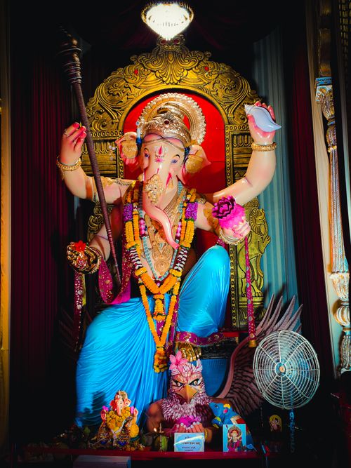 Free Colorful statue of Lord Ganesha adorned with garlands and offerings in a temple setting. Stock Photo