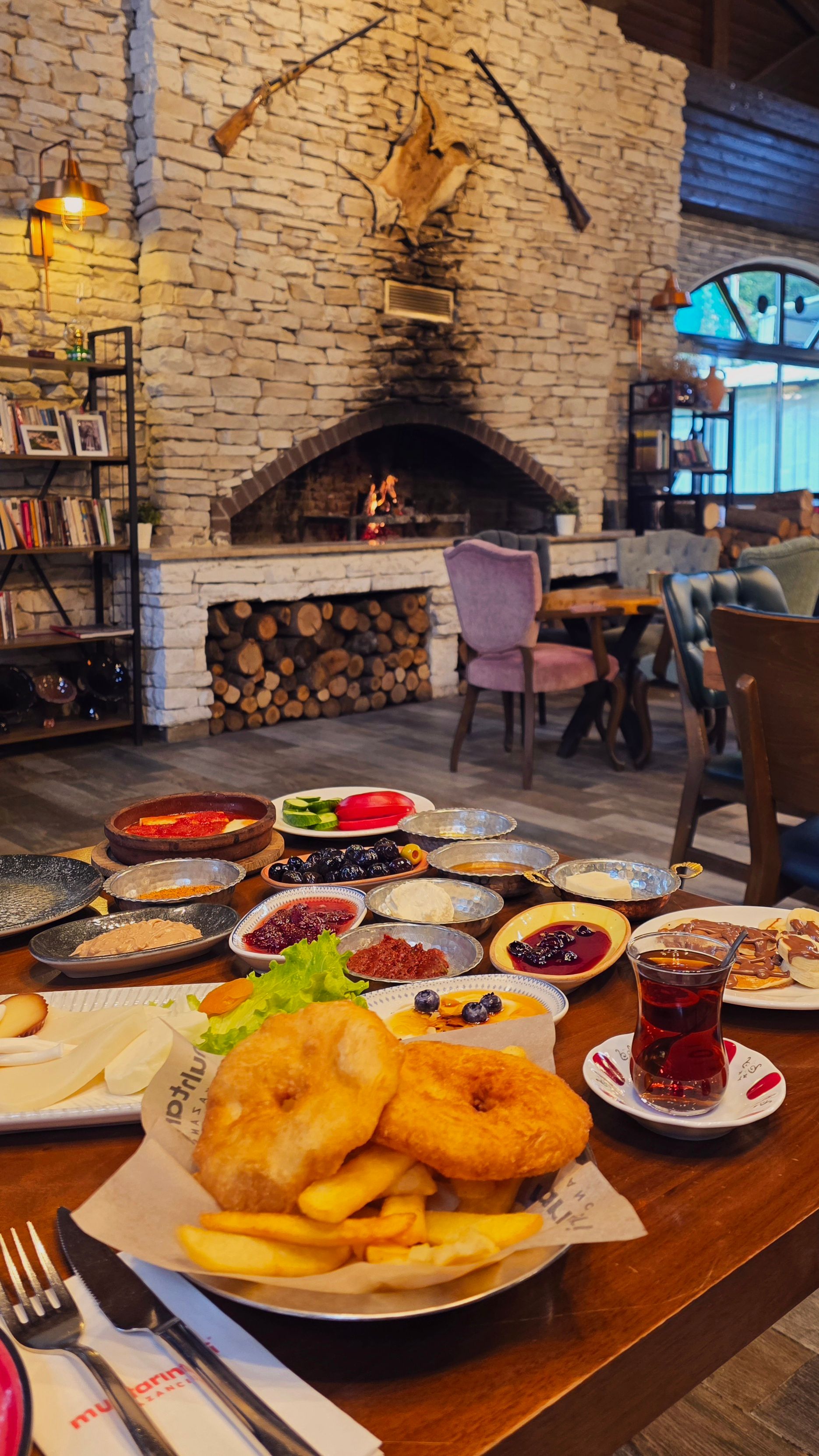 Inviting scene of a traditional Turkish breakfast in a rustic setting with a stone fireplace.