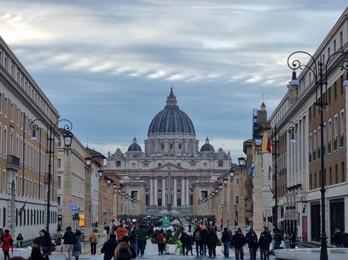 Free St. Peter's Basilica view from a bustling street in Vatican City. Stock Photo