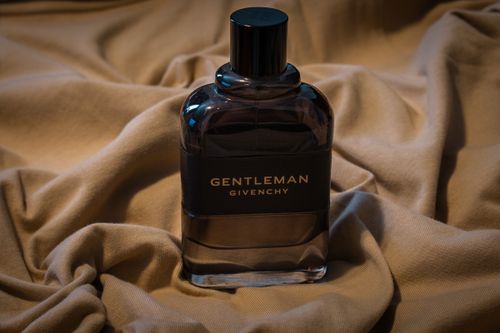 Free Luxurious Givenchy Gentleman perfume bottle elegantly placed on soft draped fabric, exuding sophistication. Stock Photo